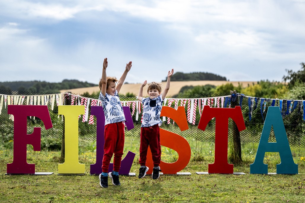 article thumb - Two boys jumping in the air in front of letters that spell Fiesta.